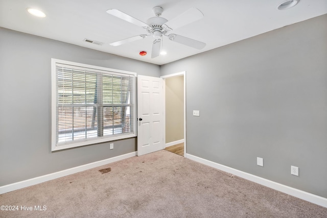 carpeted spare room featuring ceiling fan