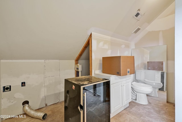 bathroom with toilet, a bidet, and lofted ceiling