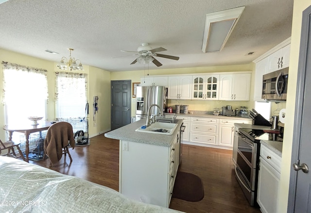 kitchen with stainless steel appliances, a center island with sink, sink, white cabinetry, and pendant lighting