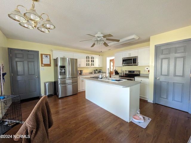 kitchen with stainless steel appliances, dark hardwood / wood-style flooring, white cabinets, a textured ceiling, and a kitchen island with sink