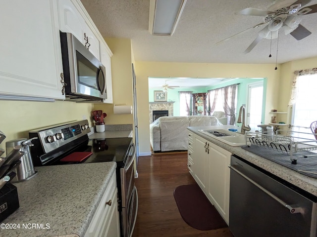 kitchen featuring appliances with stainless steel finishes, a textured ceiling, dark hardwood / wood-style flooring, sink, and white cabinets