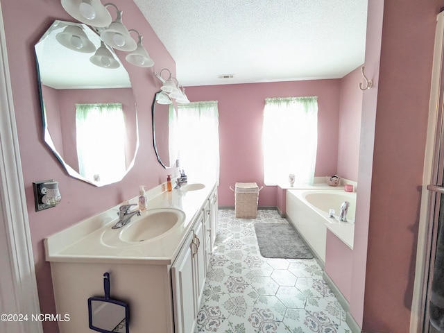 bathroom with a bathtub, vanity, a wealth of natural light, and a textured ceiling