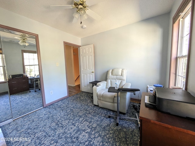 carpeted office space featuring a textured ceiling and ceiling fan