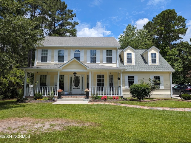 colonial home featuring covered porch and a front yard