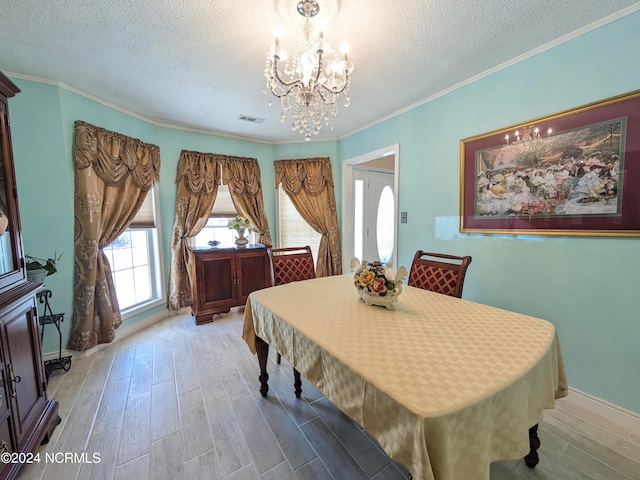 dining room featuring ornamental molding, light hardwood / wood-style flooring, a notable chandelier, and a textured ceiling