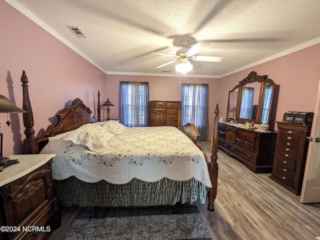 bedroom with ceiling fan, a textured ceiling, light hardwood / wood-style flooring, and crown molding