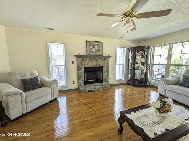 117 Longwood Dr, Stella, NC 28582 - living room with a textured ceiling, ornamental molding, a stone fireplace, wood finished floors, and a ceiling fan