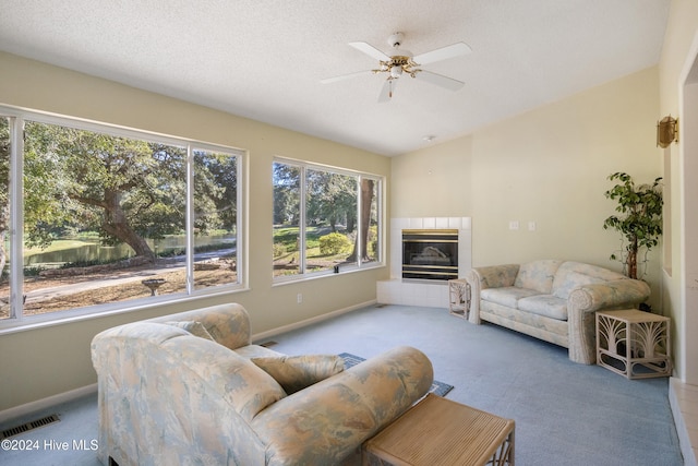 carpeted living room with a textured ceiling, a tile fireplace, ceiling fan, and lofted ceiling