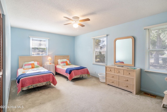 bedroom with a textured ceiling, ceiling fan, and light carpet