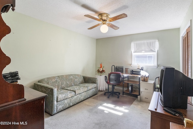 carpeted home office featuring a textured ceiling and ceiling fan