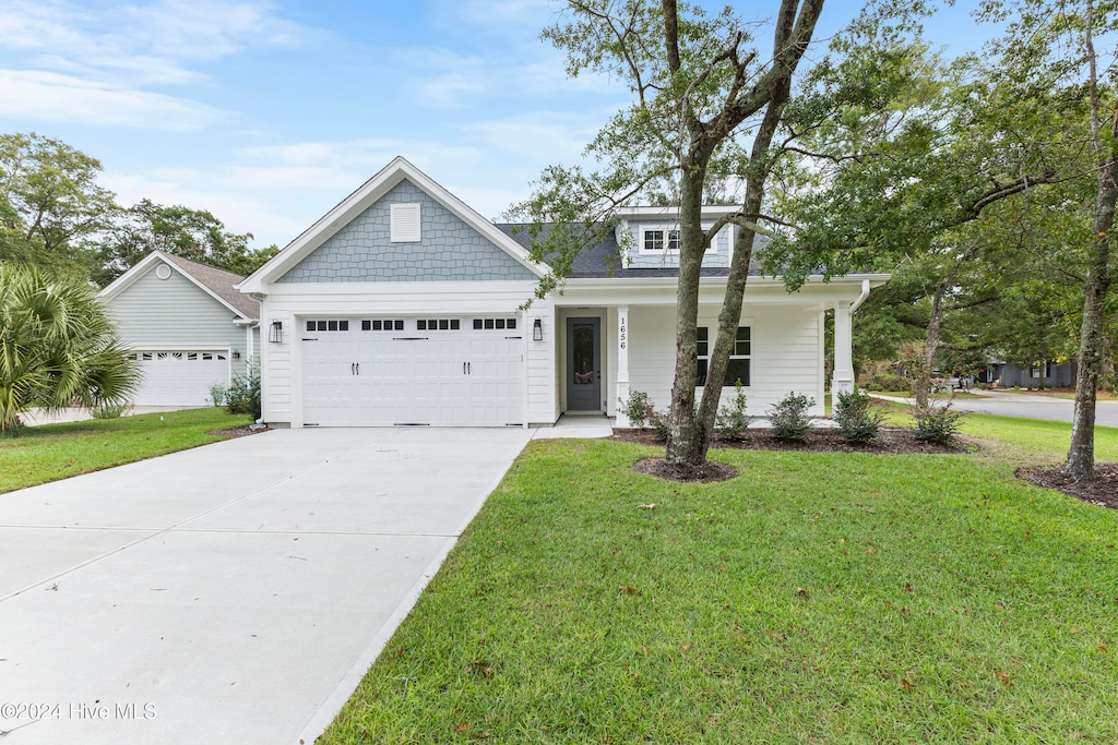 view of front of home with driveway, covered porch, an attached garage, and a front lawn