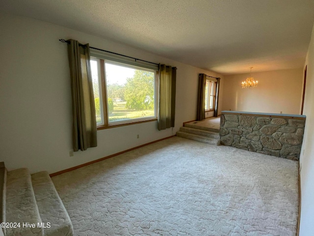 unfurnished living room featuring carpet floors, a textured ceiling, and a notable chandelier