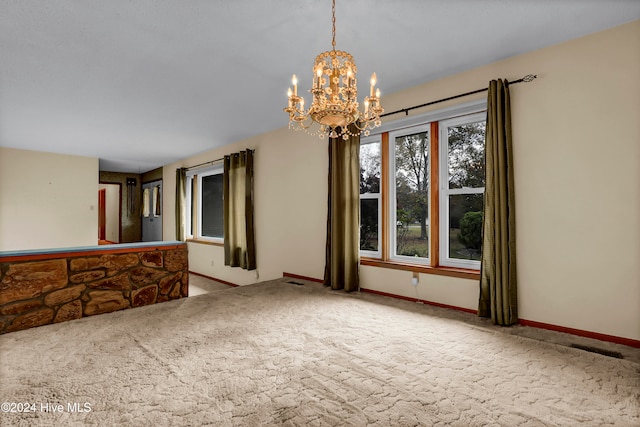 spare room featuring carpet flooring and a chandelier