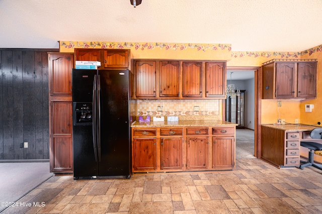 kitchen featuring a textured ceiling, tasteful backsplash, black fridge, and wooden walls