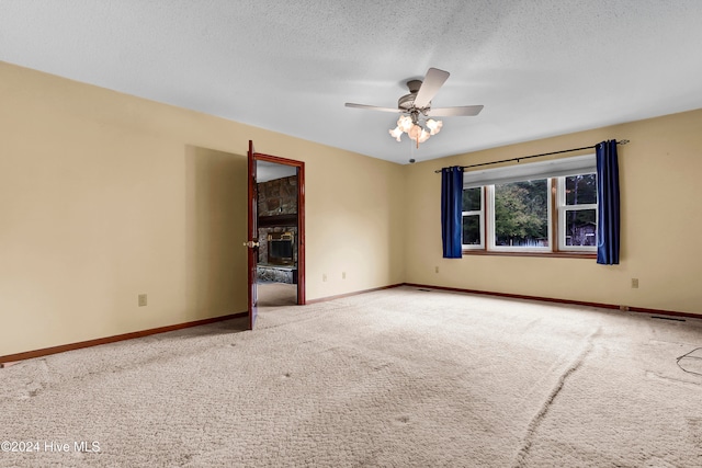 spare room featuring a textured ceiling, carpet floors, and ceiling fan