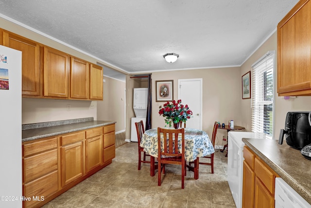 dining space featuring a textured ceiling, stacked washing maching and dryer, and crown molding