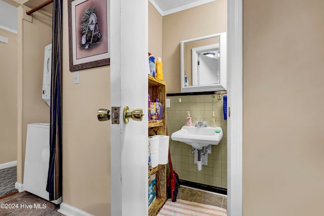 bathroom featuring stacked washer / drying machine, ornamental molding, and sink