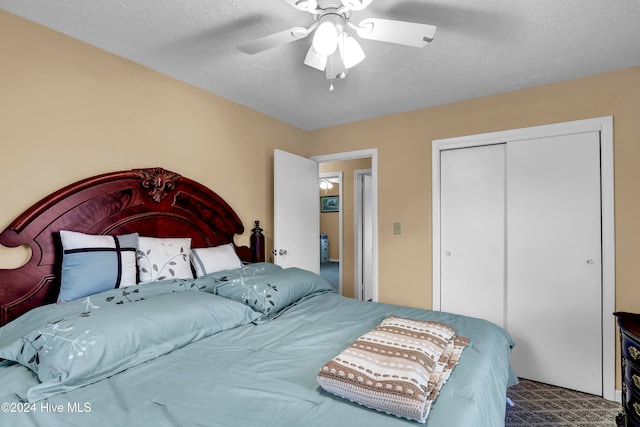 bedroom with ceiling fan, a closet, carpet floors, and a textured ceiling