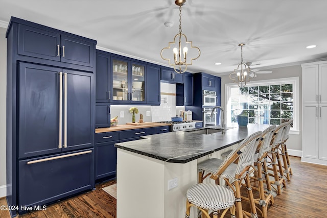1831 Hawthorne Rd, Wilmington, NC 28403 - kitchen featuring blue cabinetry, paneled refrigerator, a sink, a chandelier, and recessed lighting
