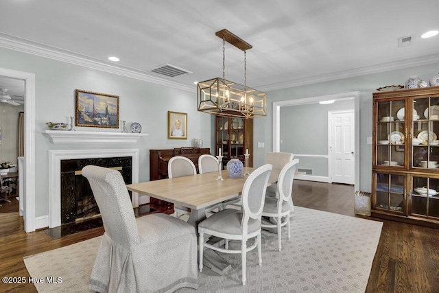 1831 Hawthorne Rd, Wilmington, NC 28403 - dining room featuring a high end fireplace, crown molding, dark wood-style floors, a chandelier, and recessed lighting