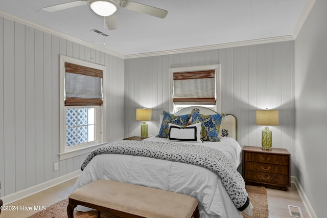 bedroom with ceiling fan, crown molding, light hardwood / wood-style floors, and wooden walls