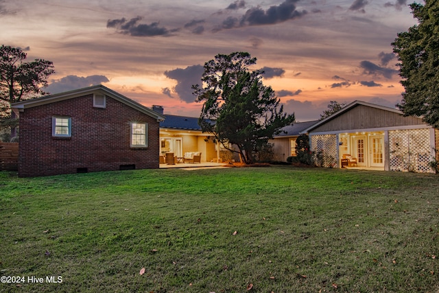 yard at dusk featuring french doors and a patio area