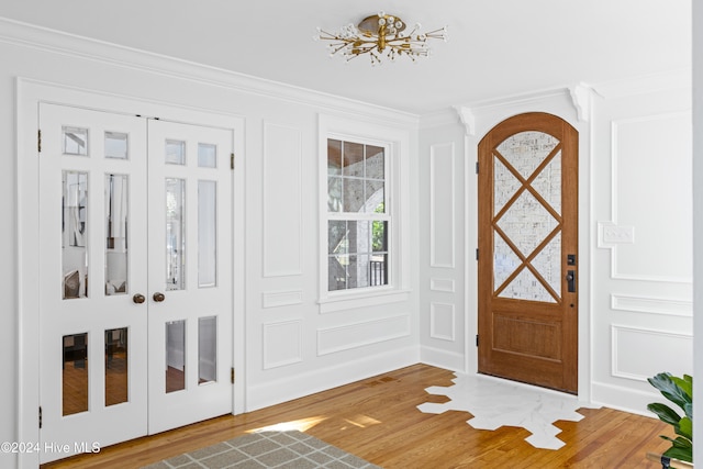 entryway with wood-type flooring and ornamental molding