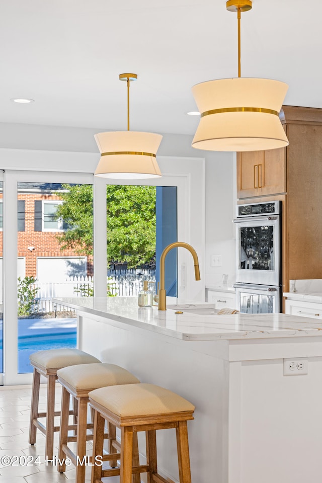 kitchen with light stone countertops, pendant lighting, and double oven