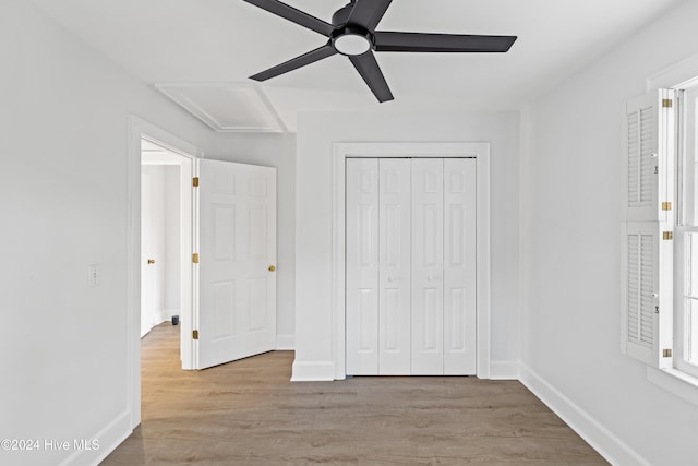 unfurnished bedroom with ceiling fan, light wood-type flooring, and a closet