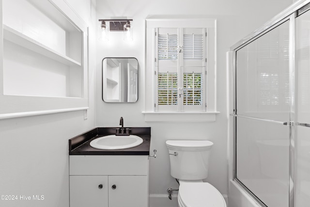 full bathroom with vanity, bath / shower combo with glass door, and toilet