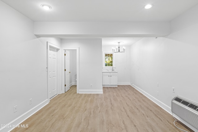 interior space featuring a chandelier, light wood-type flooring, and a wall mounted air conditioner