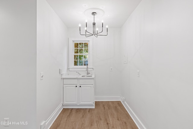 unfurnished dining area featuring a notable chandelier, light hardwood / wood-style floors, and sink