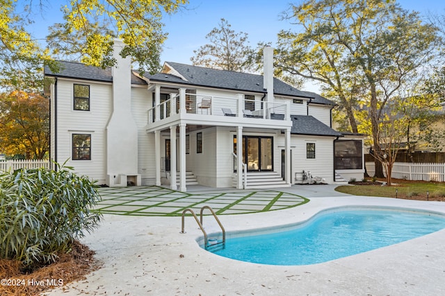 back of property featuring a patio, a balcony, and a fenced in pool