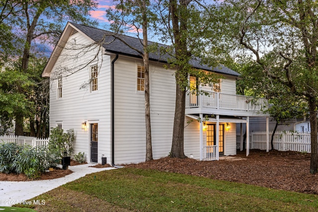 back house at dusk featuring a lawn