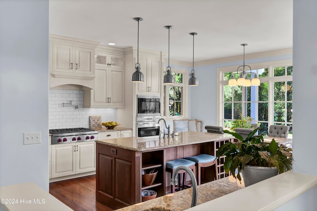 kitchen featuring dark hardwood / wood-style flooring, tasteful backsplash, light stone counters, stainless steel appliances, and a breakfast bar area