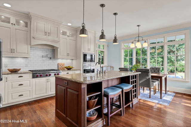 kitchen with pendant lighting, a kitchen island with sink, white cabinets, dark hardwood / wood-style floors, and stainless steel appliances