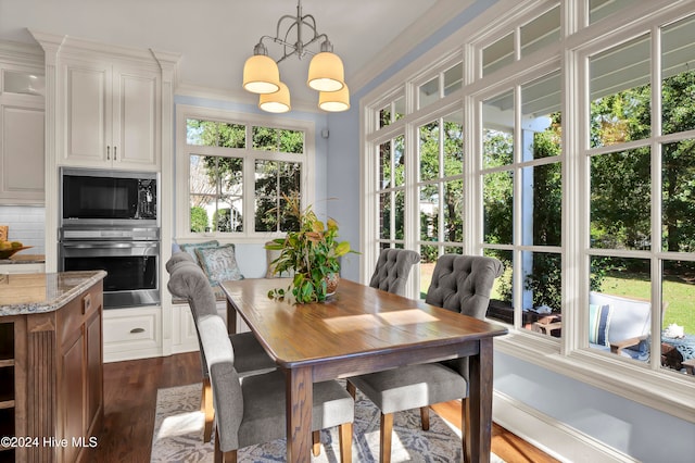 dining area with a chandelier, crown molding, and dark wood-type flooring