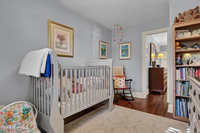 bedroom featuring dark hardwood / wood-style flooring and a nursery area