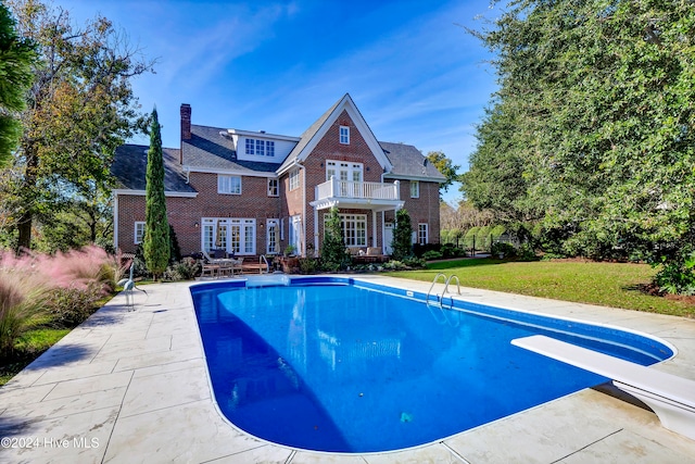 view of swimming pool with a diving board, a patio area, a yard, and french doors