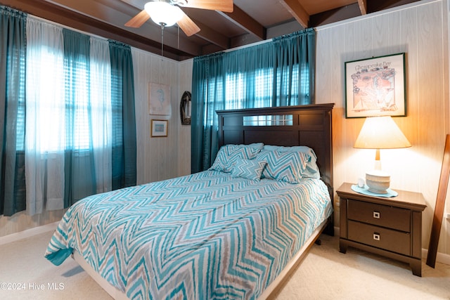 carpeted bedroom featuring beam ceiling and ceiling fan