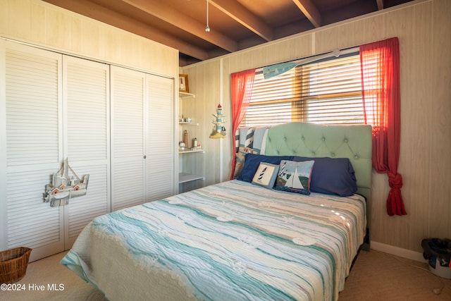 bedroom with beamed ceiling, wood walls, and a closet