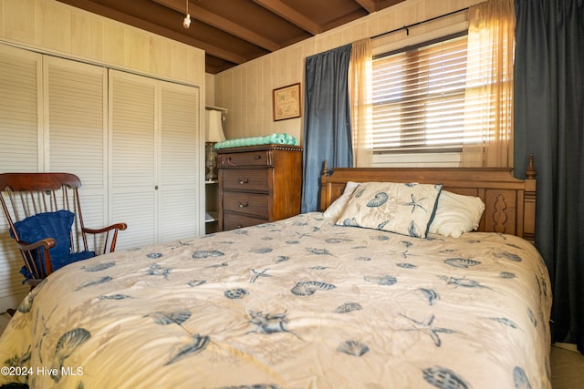 bedroom featuring beamed ceiling, a closet, and wood walls