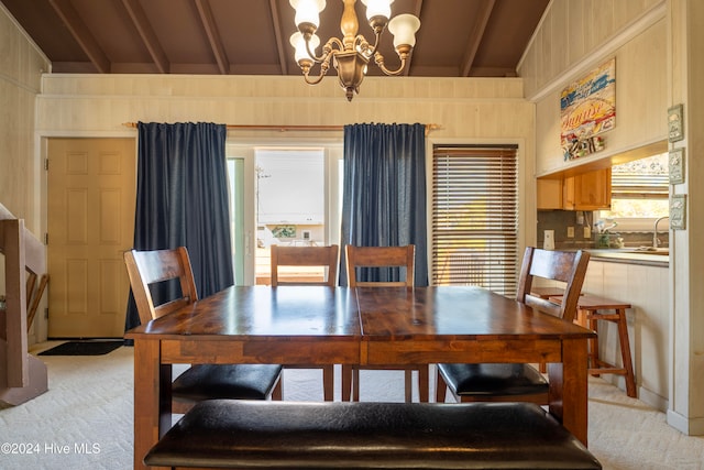 dining area featuring beam ceiling, a chandelier, and light colored carpet