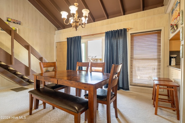 carpeted dining space featuring wood walls, lofted ceiling with beams, and an inviting chandelier