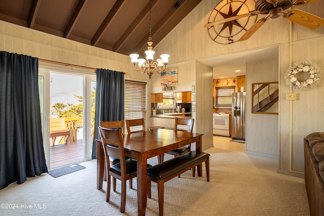 dining room with beam ceiling, ceiling fan with notable chandelier, light colored carpet, and high vaulted ceiling