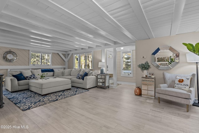 living room with beam ceiling, wood walls, and light hardwood / wood-style flooring