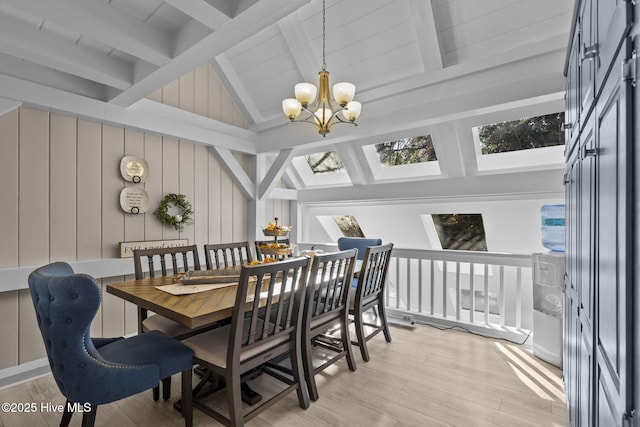 dining area featuring a skylight, high vaulted ceiling, light hardwood / wood-style flooring, beamed ceiling, and a chandelier