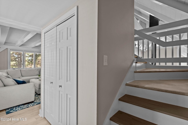 staircase featuring beam ceiling and hardwood / wood-style flooring