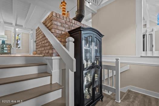 stairway with hardwood / wood-style floors and beam ceiling