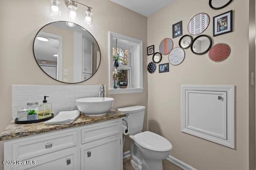 bathroom featuring vanity, toilet, and backsplash